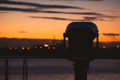 Close-up of silhouette light against sea during sunset