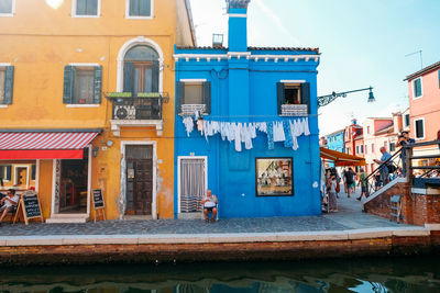 Residential buildings by canal against blue sky