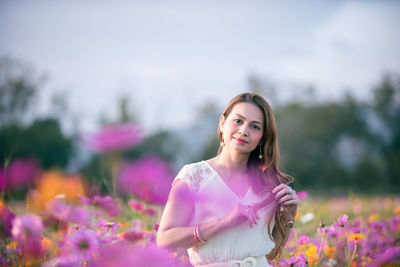 Portrait of woman with pink flowers against blurred background