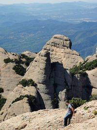 People on rock by mountains