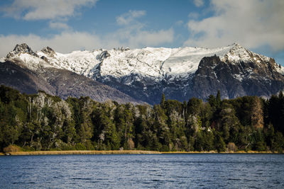 Scenic view of lake by snowcapped mountains against sky