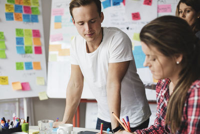 Businessman looking at work of colleague on table in creative office