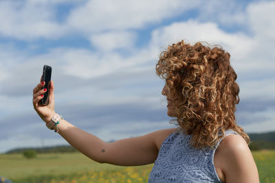 Rear view of woman with arms raised against sky