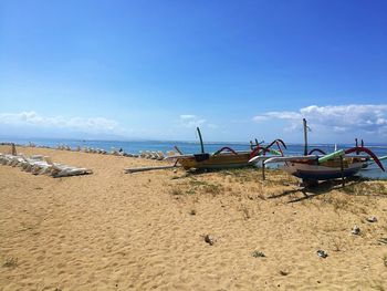 Fishing boats moored on beach against sky