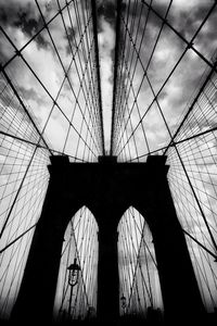 Low angle view of suspension bridge against cloudy sky