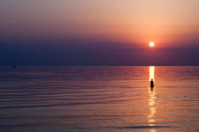 Silhouette of man looking at sea against sky during sunset