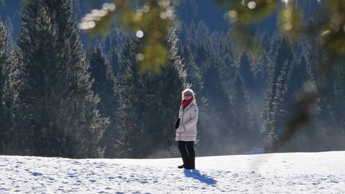 Rear view of woman standing on snow covered field