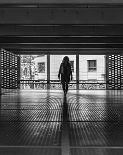 Rear view of woman walking on footpath against building