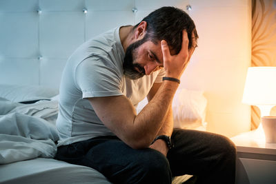 Person with some kind of problem sitting on the bed and shaking their head while stirring their hair