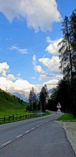 Road by trees against sky