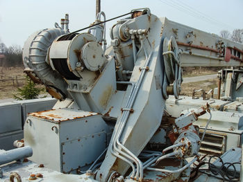 Close-up of abandoned machinery on field against sky