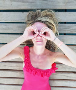 High angle portrait of woman gesturing while lying on hardwood floor