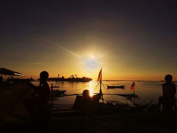 Silhouette people on beach against sky during sunset