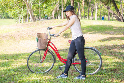 Full length of woman with bicycle standing on field