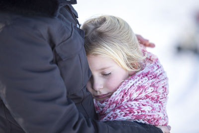 Girl cuddling with her mother in winter