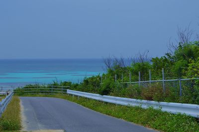 Road by sea against clear blue sky