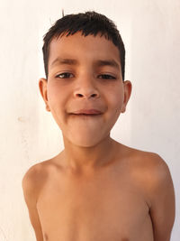 Portrait of shirtless boy against wall