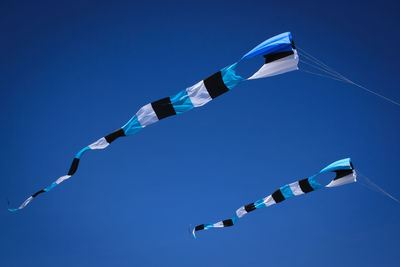 Low angle view of kites against clear blue sky