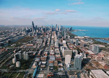 Aerial view of cityscape by sea against sky