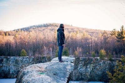 Rear view of man standing on rock against sky