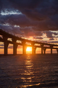 Bridge over sea against sky during sunset