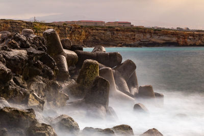 Scenic view of rocks in sea against sky