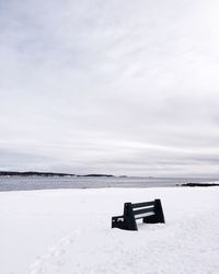 Empty bench on snowed landscape