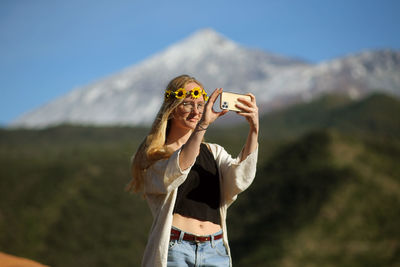 Midsection of woman holding umbrella against mountains