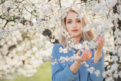 Portrait of young woman in the flowered garden in the spring time. almond flowers blossoms