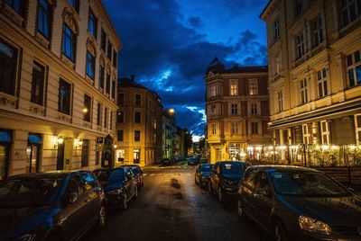 Illuminated street amidst buildings in city at night