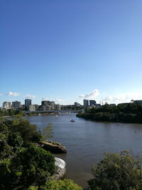 River by buildings in city against clear sky