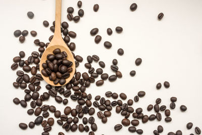 Directly above shot of roasted coffee beans in spoon on table