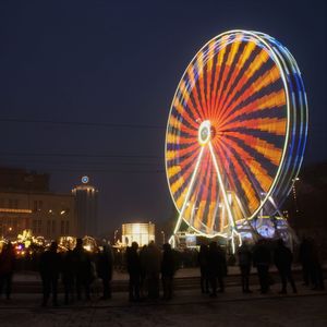 People at amusement park against sky at night