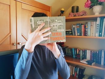 Midsection of person reading book at home