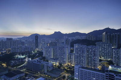 High angle view of illuminated buildings in city against blue sky