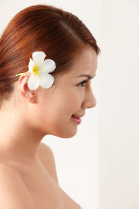 Close-up of woman wearing flower against white background