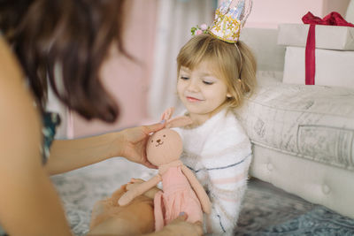 Close-up of mother giving toy to cute girl at home