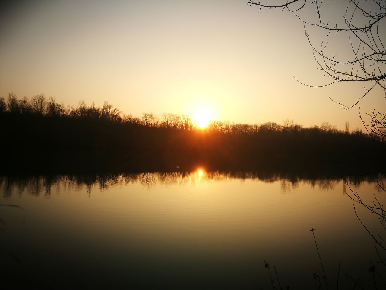 REFLECTION OF SILHOUETTE TREES ON LAKE AGAINST SKY DURING SUNSET