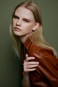 Portrait of beautiful young woman against wall