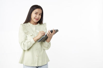 Smiling young woman using smart phone against white background