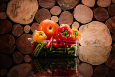 Close-up of vegetables in container against stacked logs