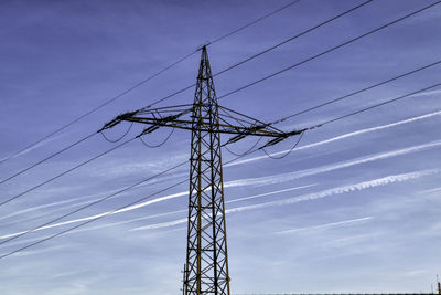 Low angle view of electricity pylon against blue sky