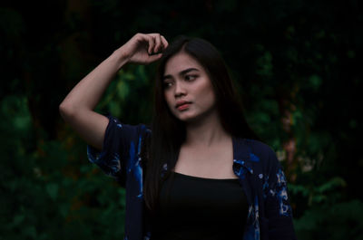 Young woman looking away while standing in forest