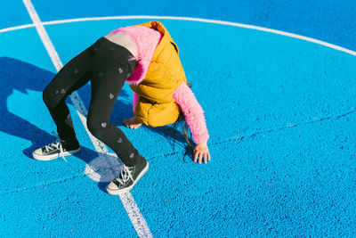 Girl doing acrobatic activity on soccer court during sunny day