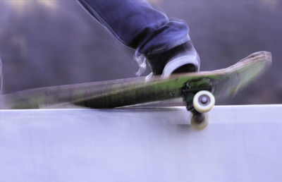 Close-up of person skateboarding on retaining wall