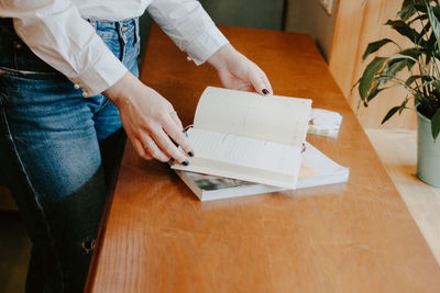 Midsection of woman reading books on table