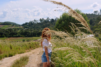 Side view of young woman standing at field