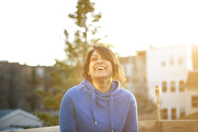 Cheerful woman standing against sky during sunset