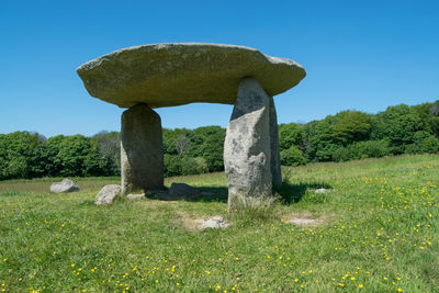 Stone structure on field against clear sky