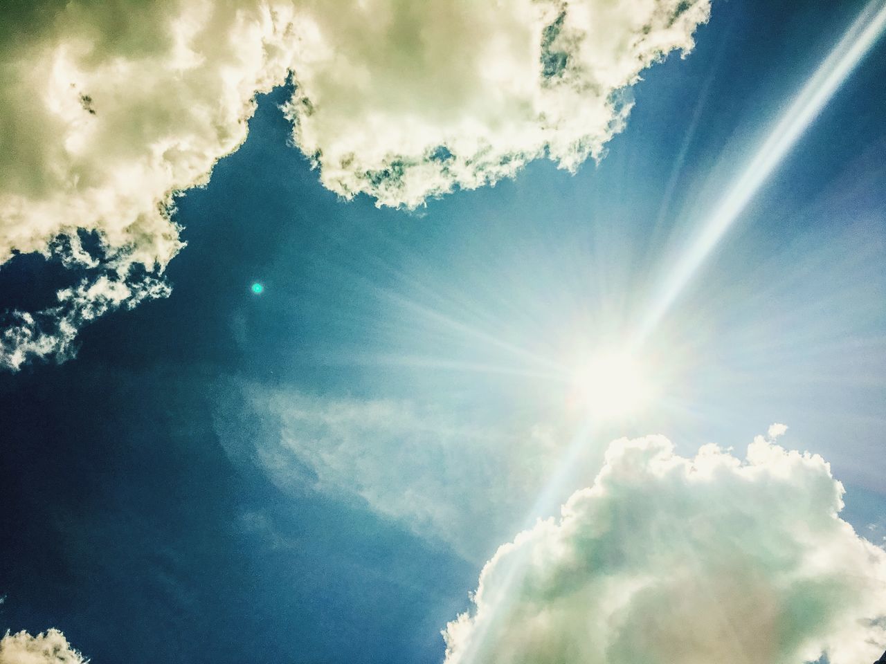 LOW ANGLE VIEW OF SUNLIGHT STREAMING THROUGH CLOUDS IN SKY